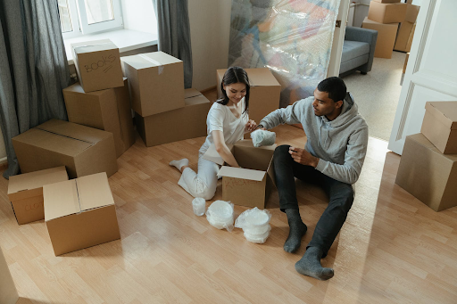 Two people packing a box surrounded by boxes