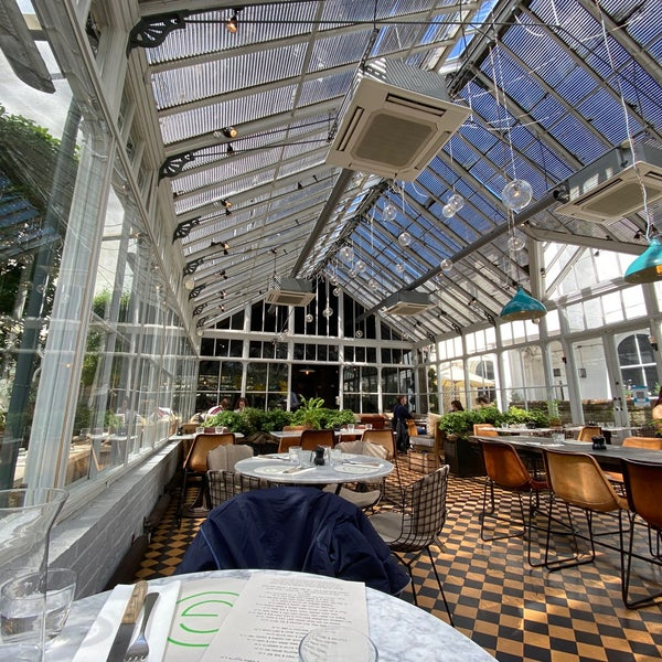 restaurant set in a a Victorian glass greenhouse with lights suspended from the ceiling